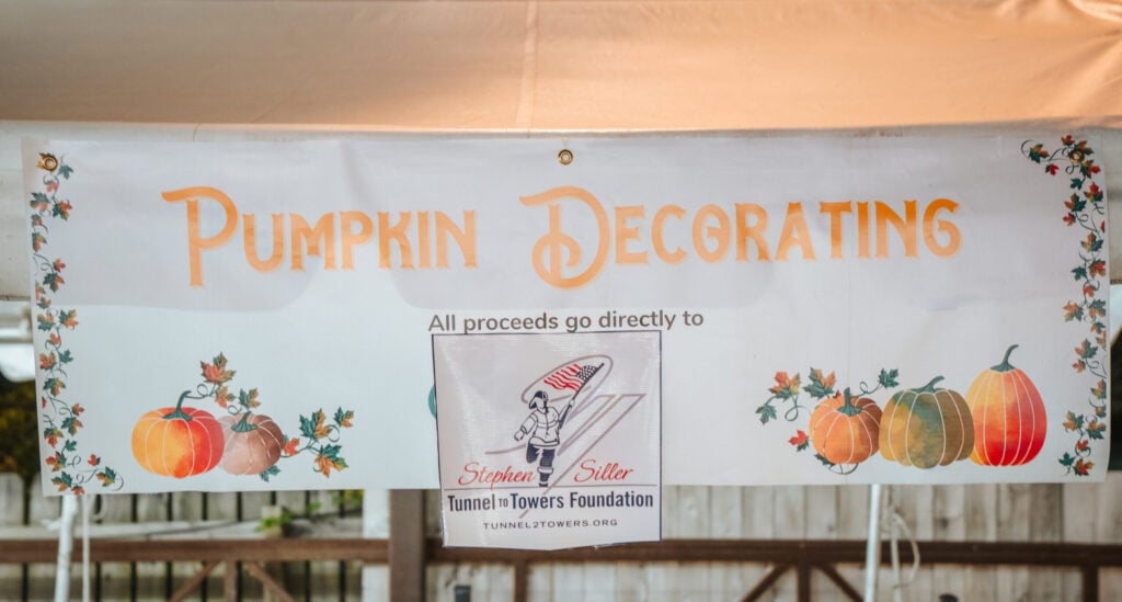 Photo from Knowledge Services' 2023 Fall Fest showing a sign that says that all proceeds from Pumpkin Decorating go directly to the Stephen Siller Tunnel to Towers Foundation. 