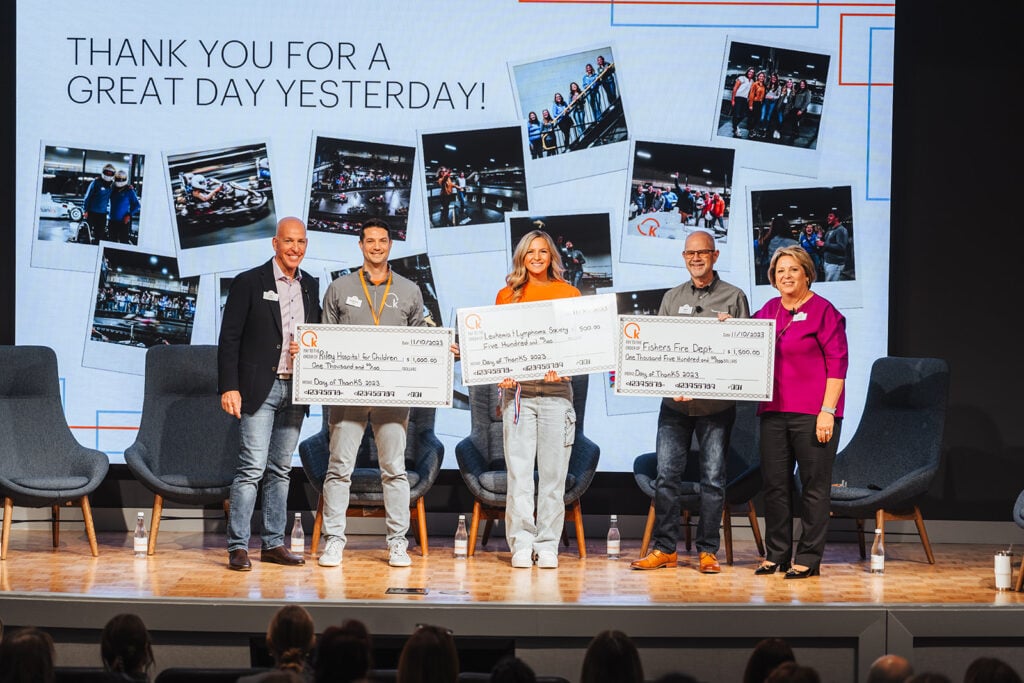 Photograph of Knowledge Services' Day of ThanKS 2023 where three department heads are holding giant checks for money raised for charities.