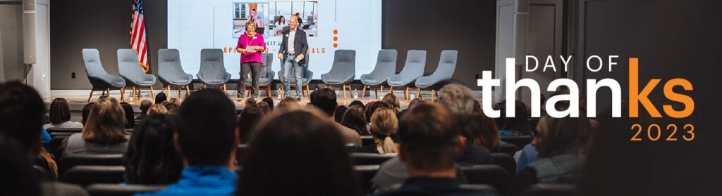 Photo of CEO Julie Bielawski and President Joe Bielawski on stage in front of audience of employees during Knowledge Services' Day of ThanKS celebration in 2023.