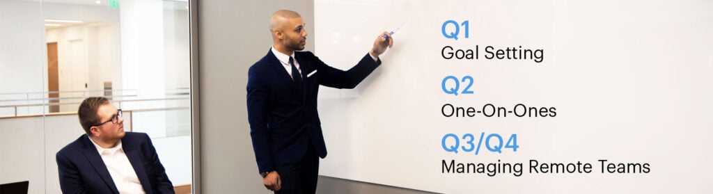Photo of two male employees looking at a whiteboard with text: "First Quarter: Goal Setting. Second Quarter: One-on-Ones. Third and Fourth Quarter: Managing remote teams.