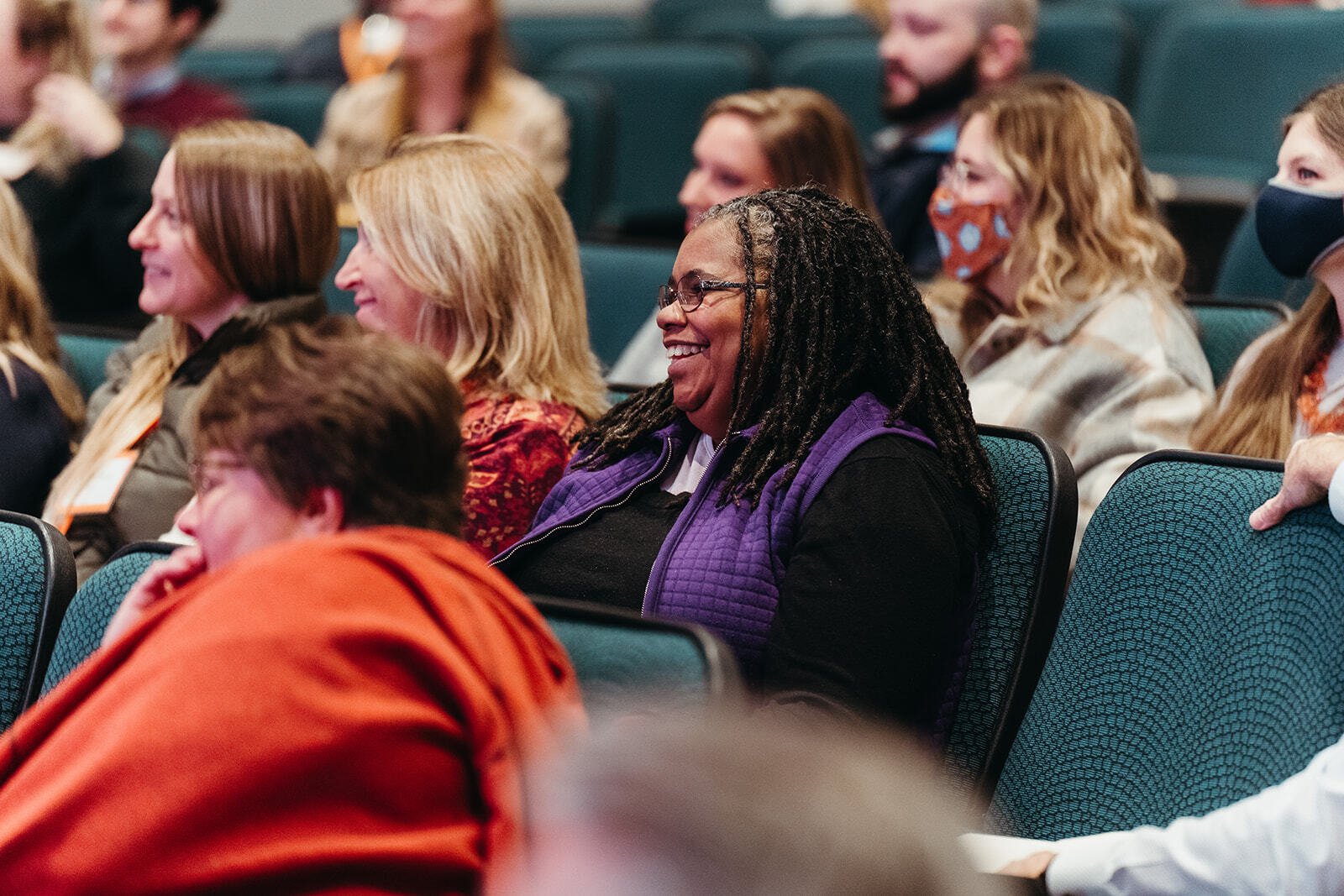 A group of people sitting in an auditorium, smiling.