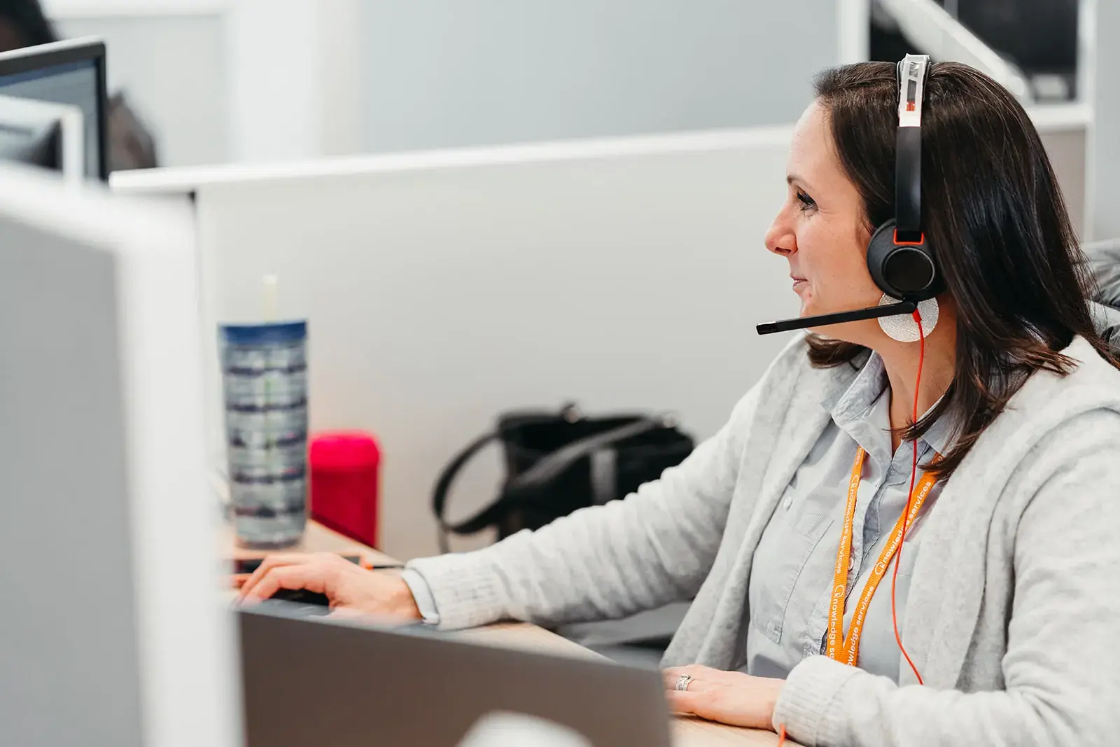 A woman with a headset working at a computer.
