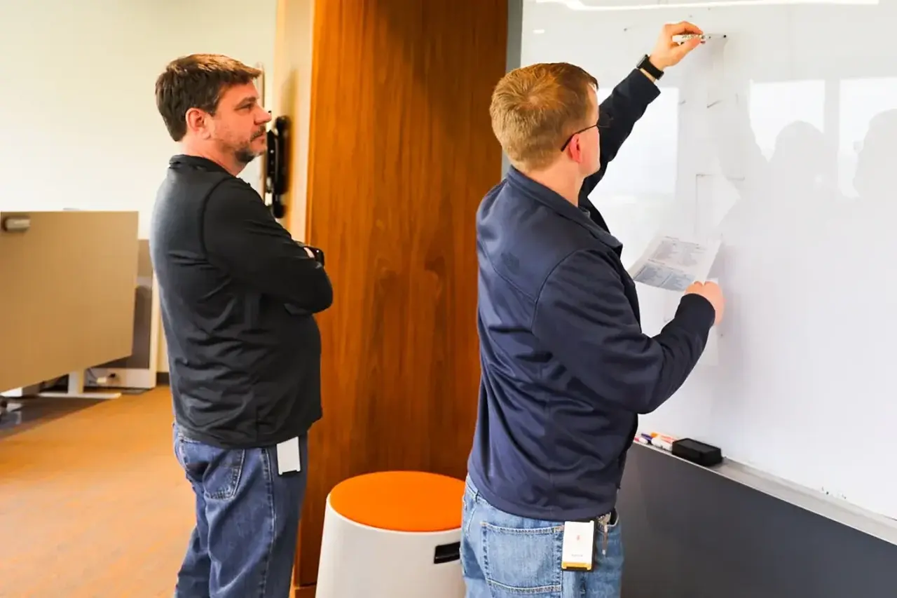 Image of two men writing on a whiteboard
