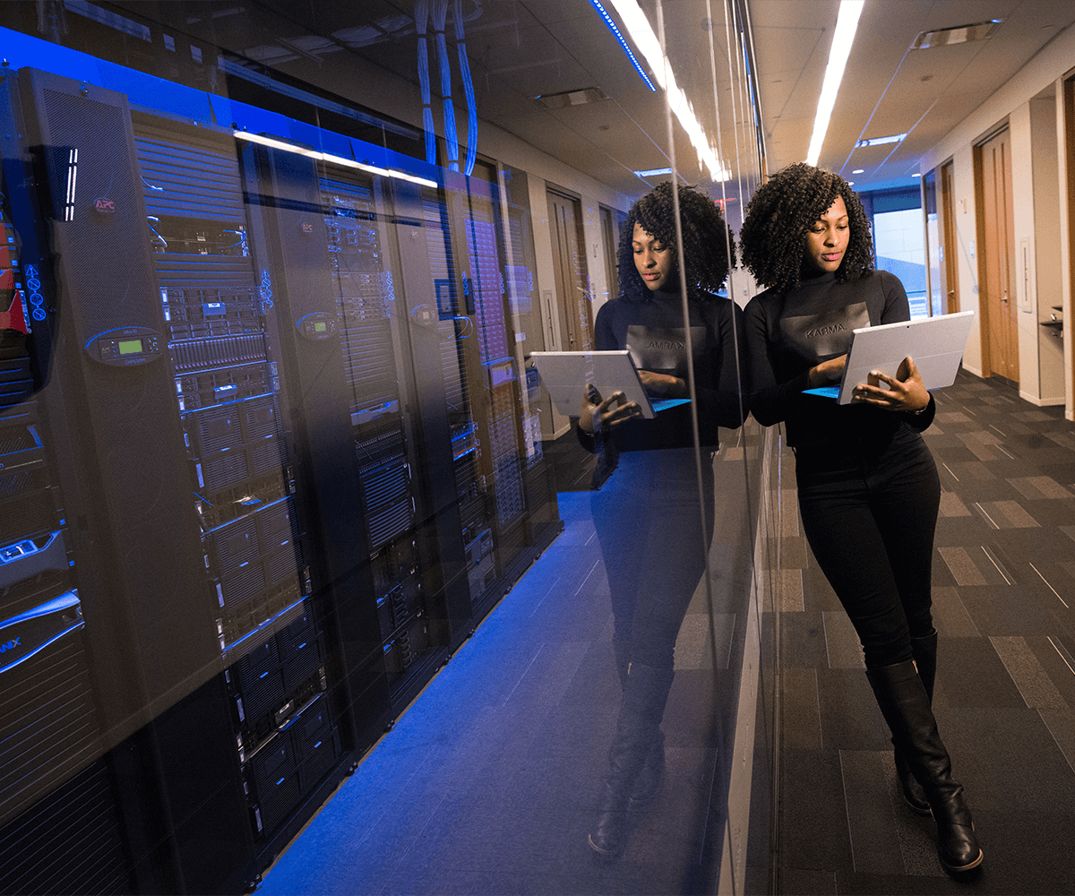 Image of woman standing outside of server room on her computer